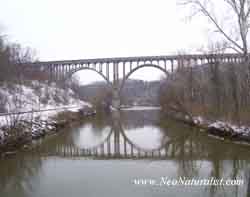 A wallpaper picture of the Cuyahoga River in the winter, with snow.  The State Route 82 Bridge Reflects in the calm water.
